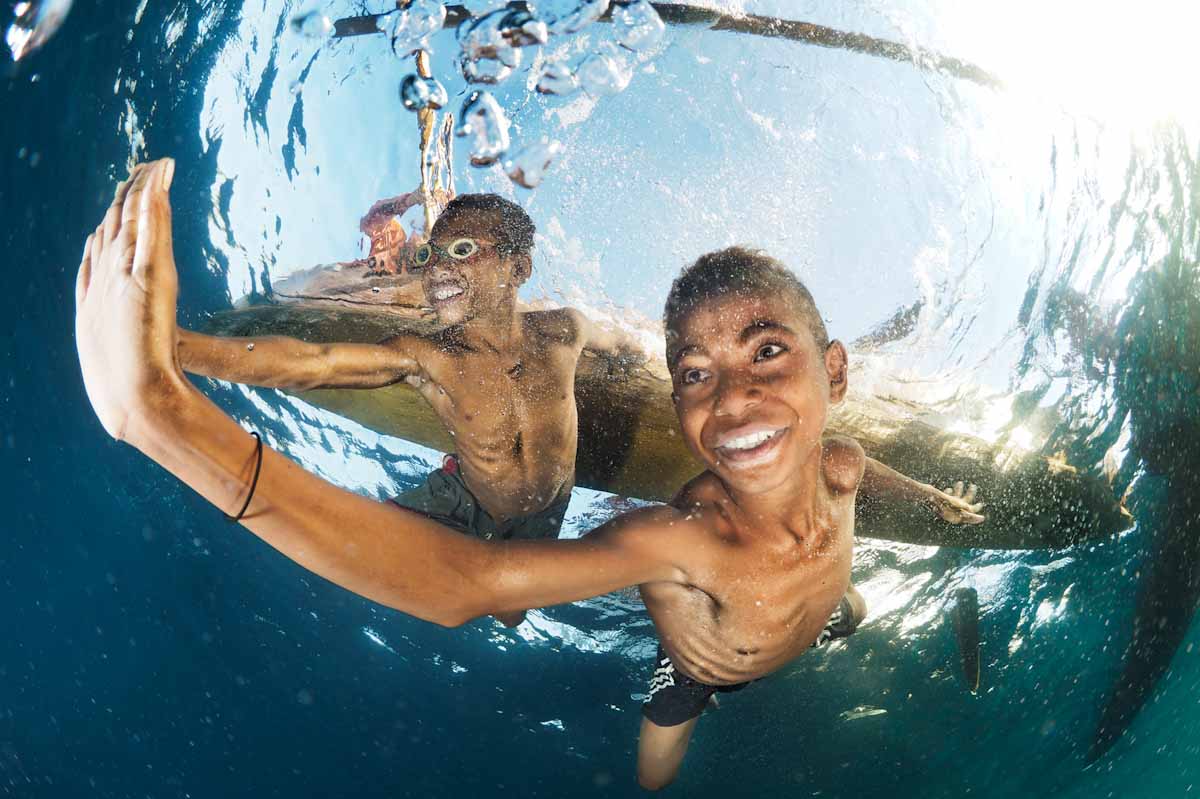 Alor kids performing free diving under their canoes